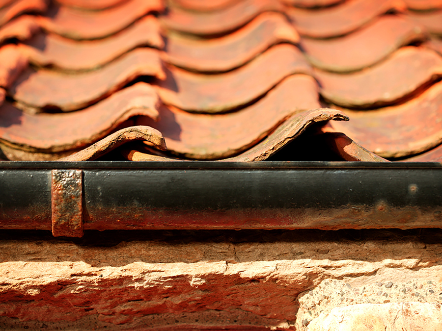 Orange pantiles on a roof with a black gutter beneath them