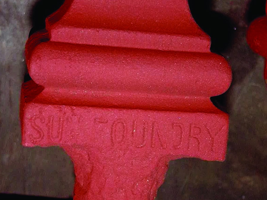 A red piece of cast iron with a 'Sun Foundry' stamp on it