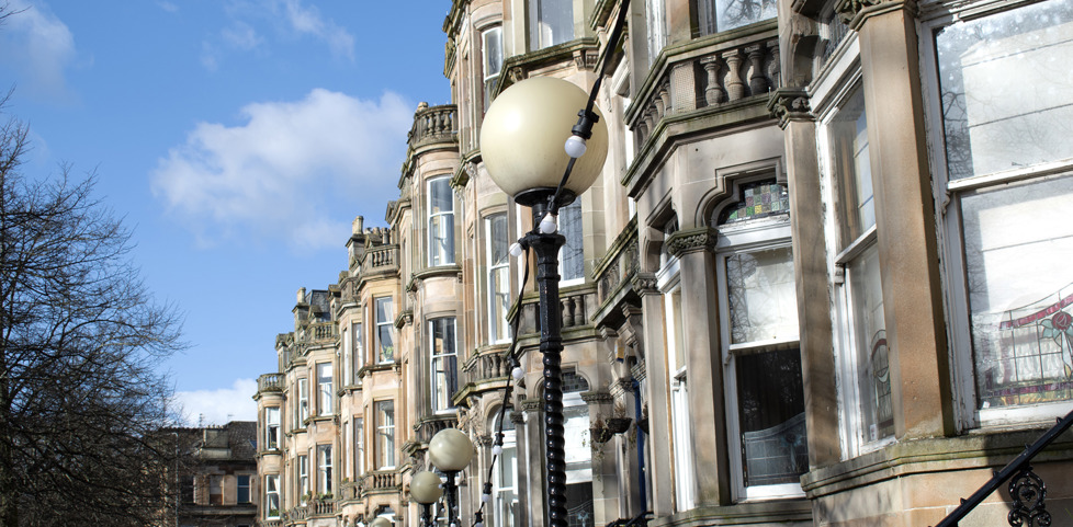 A row of blonde sandstone tenements with sash and case windows in the city.