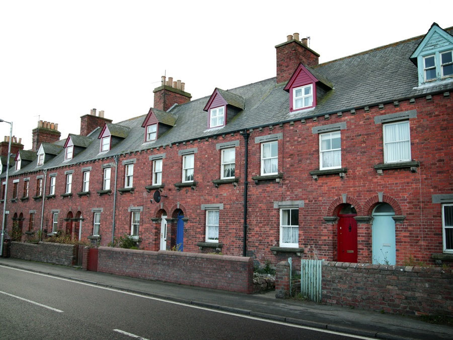 A row of brick terraced houses, with slate roofs and dormer windows