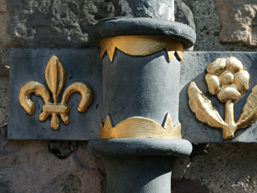 The ironwork collar of a downpipe with gold, gilded floral designs on it