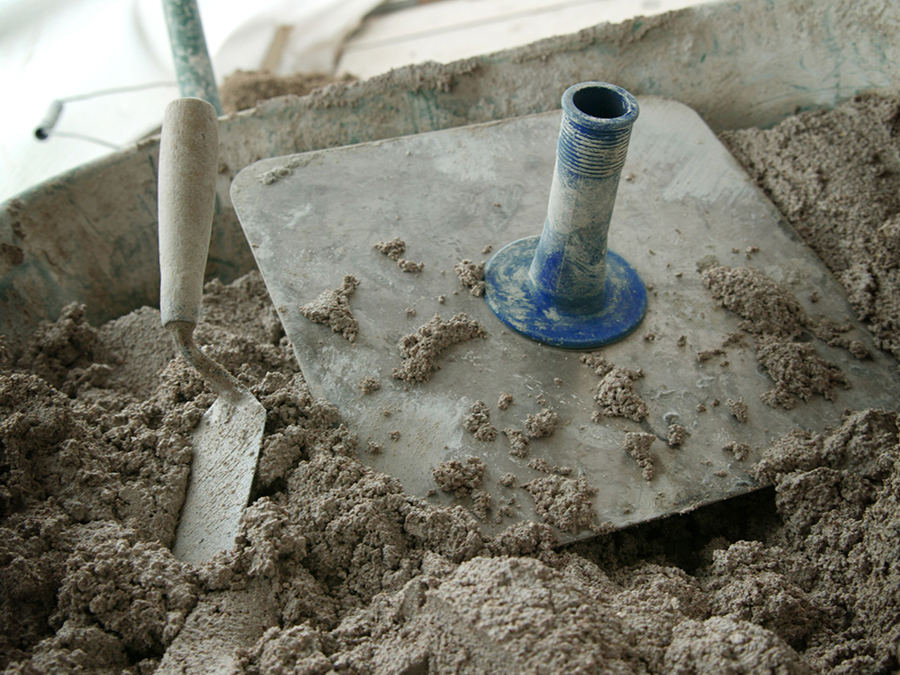 A bucket of lime mortar with a plasters hawk on top of it