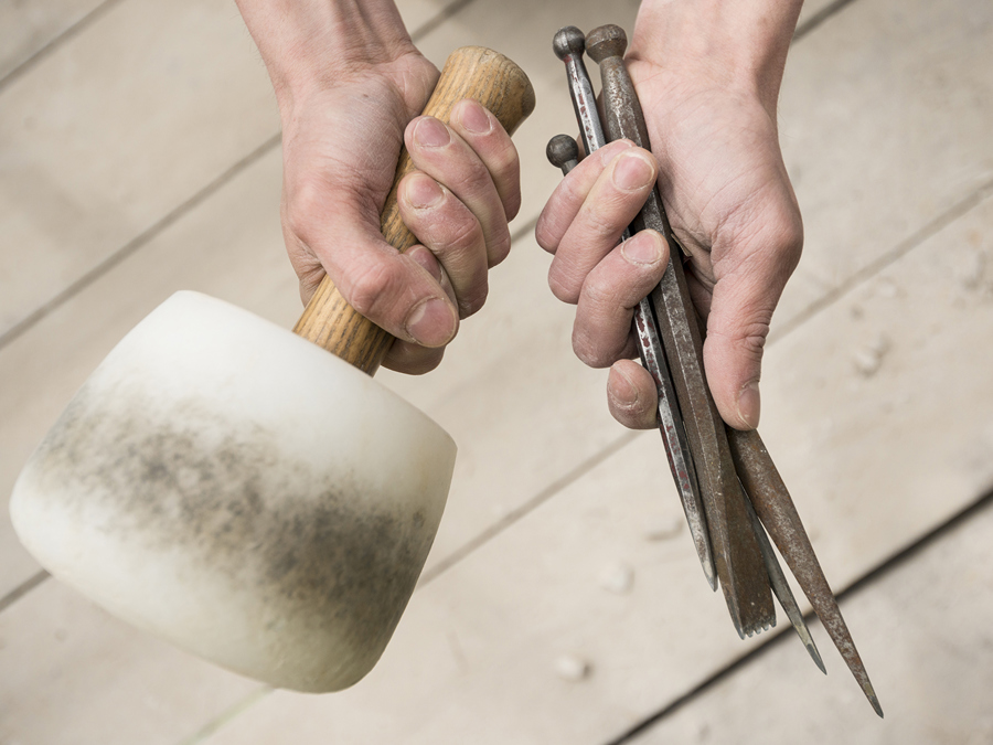Someone holding stonemasons tools in their hands
