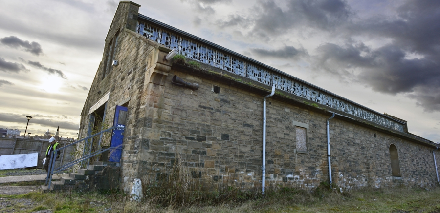 The original, long, stone Engine Shed building, abandoned and surrounded by vegetation