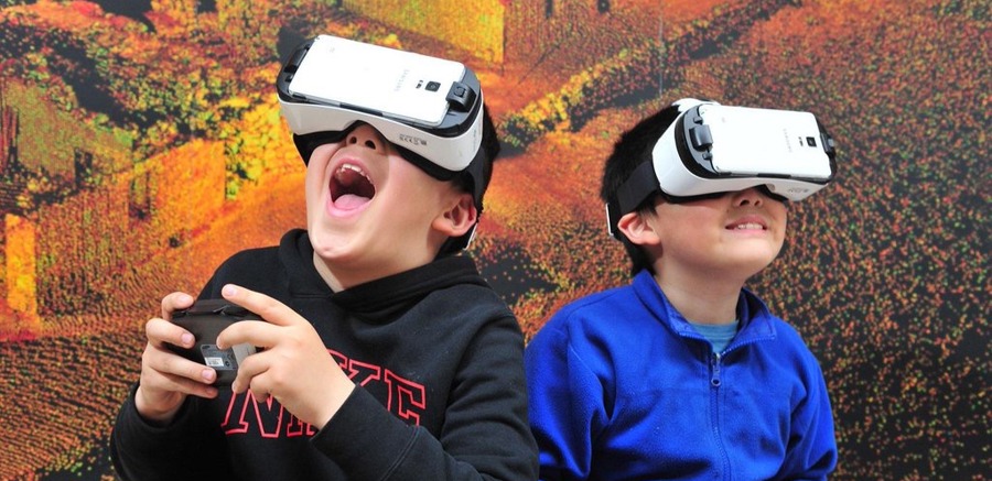 Two boys try out virtual reality headsets.