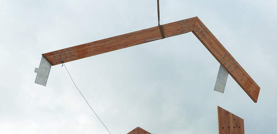 A large, wooden beam being lowered onto the Engine Shed building