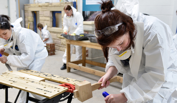 A group of people chiseling wood in a workshop