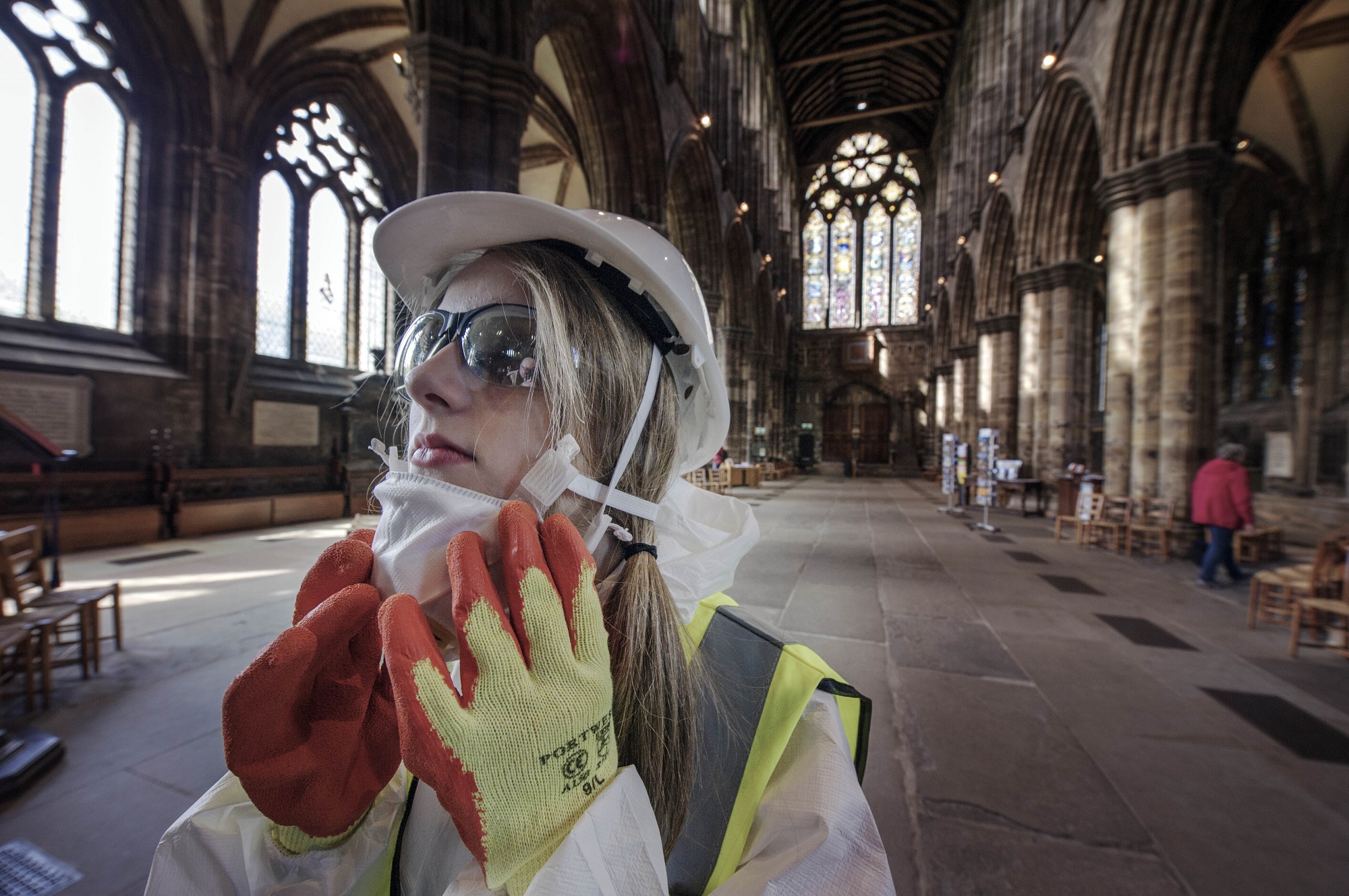 Someone standing inside Glasgow Cathedral wearing safety equipment