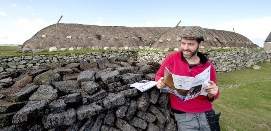 Someone looking at plans while standing outside a rural traditional building