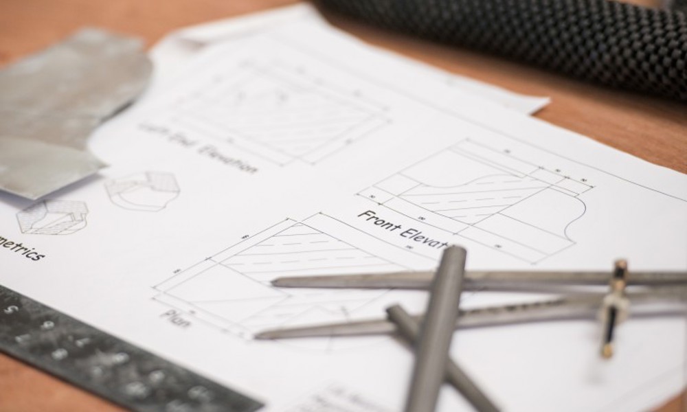 Papers with building repair designs and drawing tools on top of a table