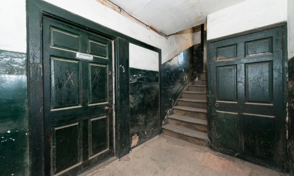 A building at risk with green doors and a concrete floor