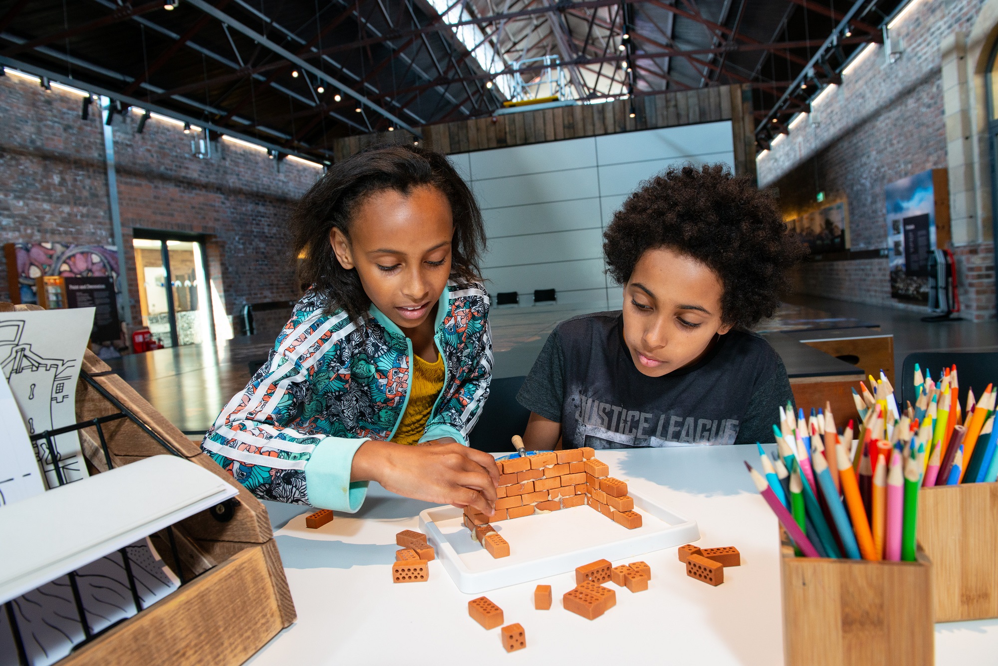 Two children building a wall from mini bricks inside the Engine Shed