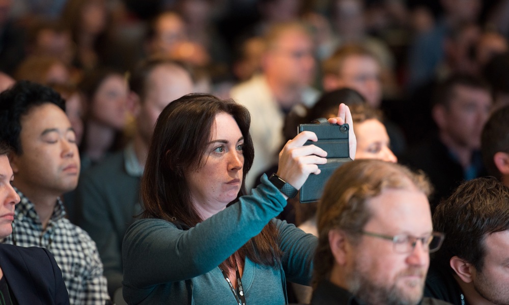 A person in a crowd holds up their phone to take a photo