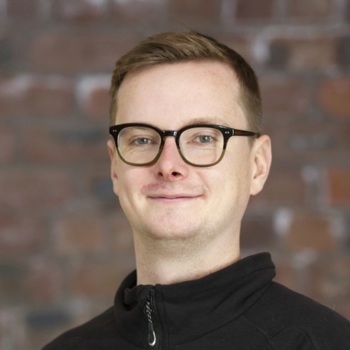 A headshot of Martin smiling, wearing black glasses