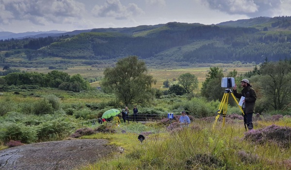 A person laser scanning historic rocks in a beautiful, wild landscape
