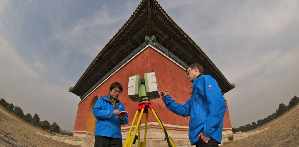 Two people standing outside a historic building with a laser scanner