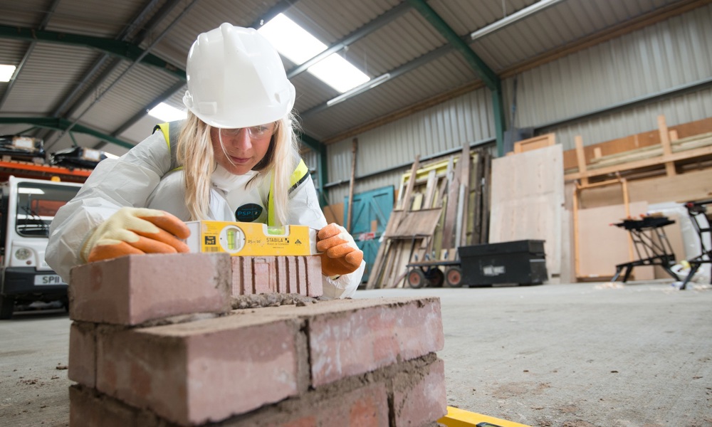 A person laying bricks inside an industrial workshop