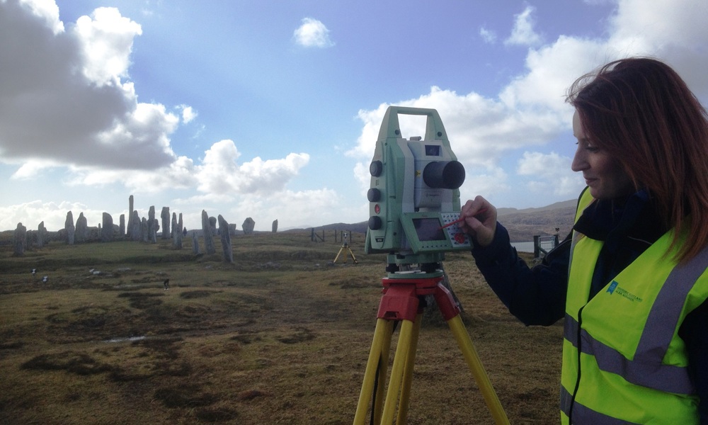 A person operating a laser scanner in a field
