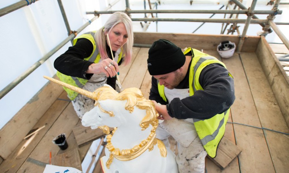 Two people gilding a stone unicorn