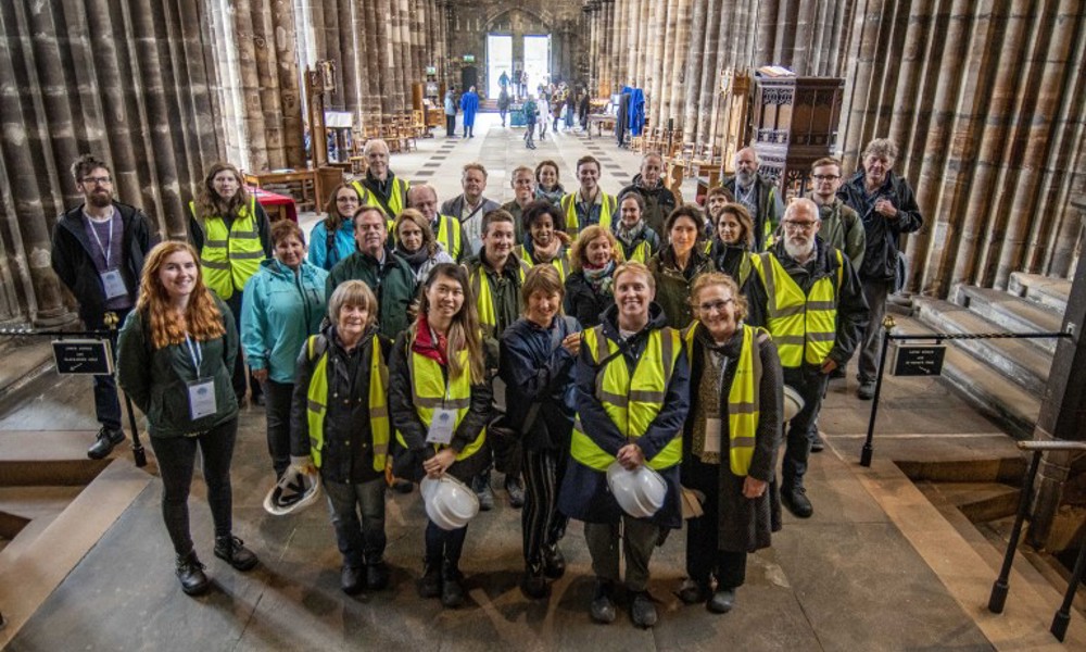 A large group of people wearing high vis vests, standing inside a historic cathedral