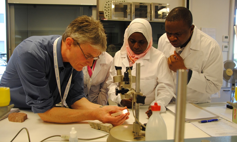 A person demonstrating how to examine stone in a lab to three other people