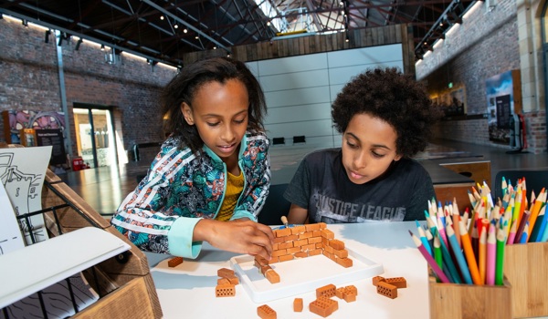 Two children making a wall out of tiny mini bricks