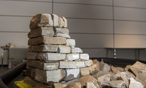 A small dry stone wall being made on a table