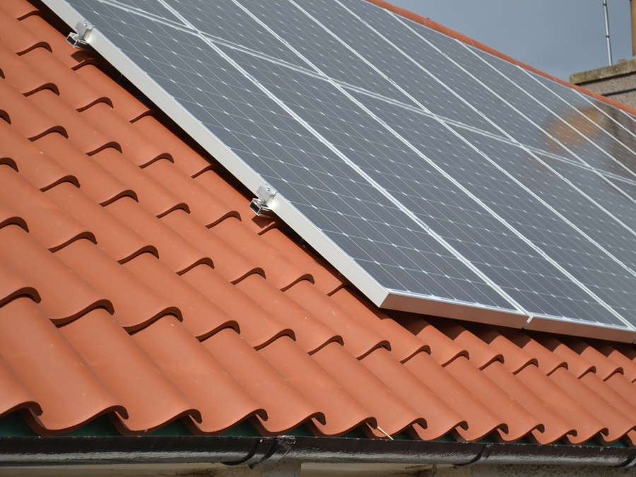 An orange pantile roof with solar panels attached to it