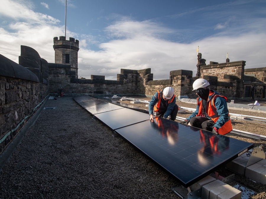 Two people installing solar panels on the roof of Edinburgh Castle