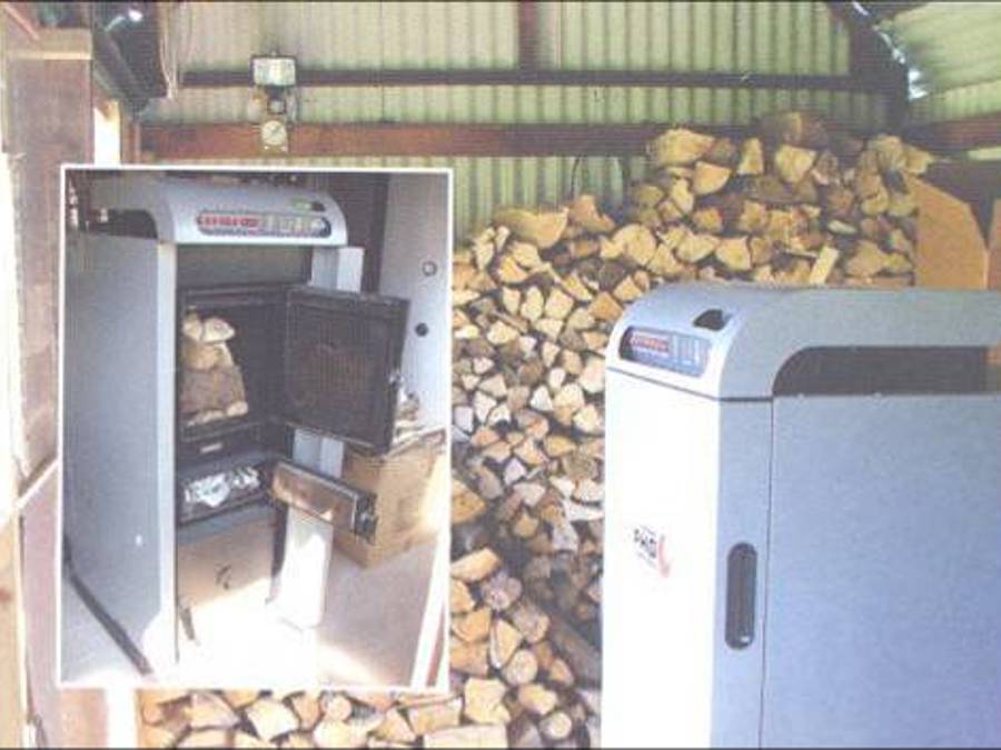 A large boiler surrounded by firewood