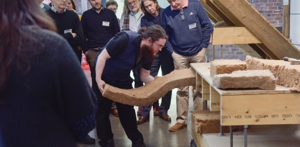 A member of HES staff, surrounded by a group of people at the Engine Shed. The staff member is displaying insulation techniques on a scale model. 