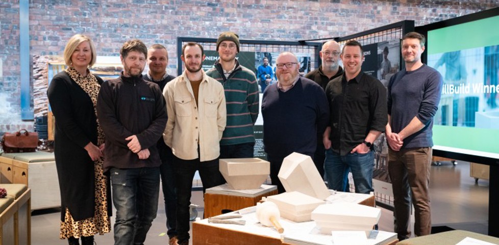 A group of people standing inside the Engine Shed in front of a table with stone carvings on it