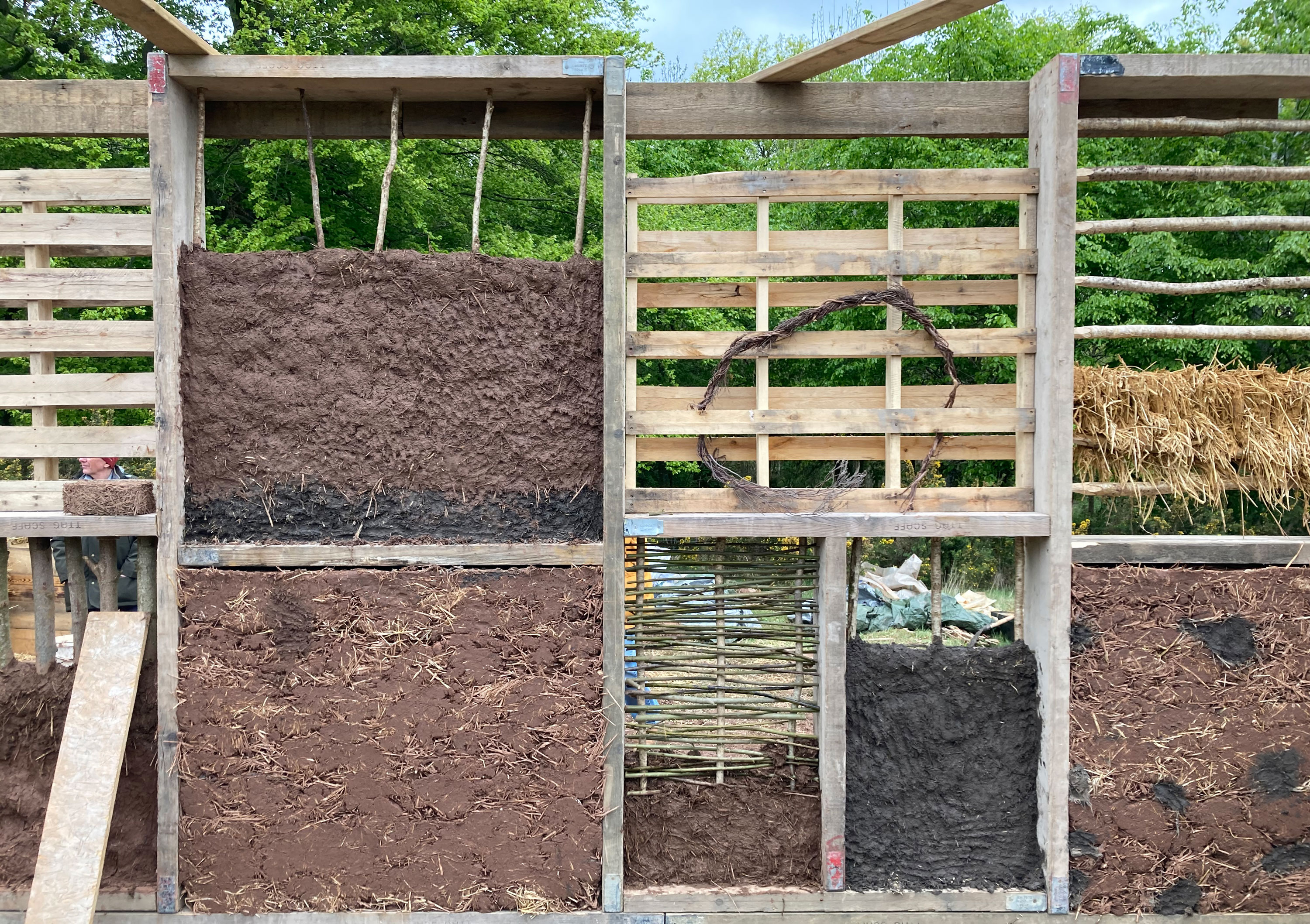 A wooden frame with a series of box compartments. Each section is showing different ways of packing earth into the wall section. 