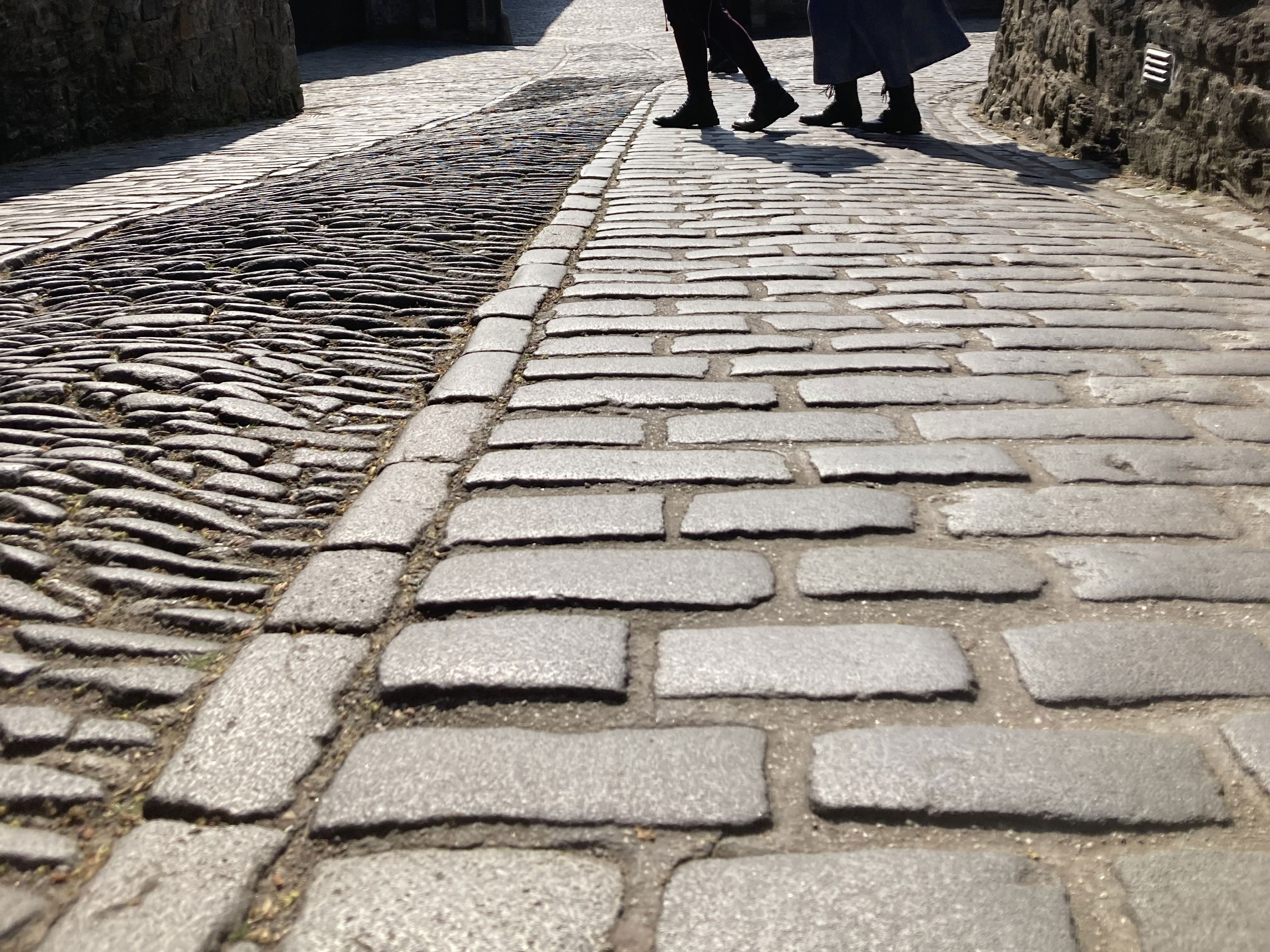 A view looking down a stone cobbled street in Scotland. With stone walls on either side. 
