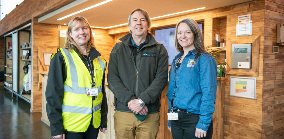 Three members of staff. The first on left is wearing a high-vis vest and lanyard, the next is wearing a branded green fleece and the third is wearing a branded denimn shirt. 